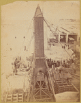 The crated obelisk "Cleopatra's Needle" secured by ropes to machinery prior to being lowered to a horizontal position 