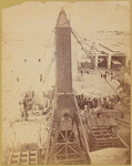 The crated obelisk "Cleopatra's Needle" secured by ropes to machinery prior to being lowered to a horizontal position 