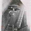 Mrs. A. Murray in the common area of her residence, with an umbrella under a leaking stairwell, at 61 East 117th Street, Harlem, New York, 1951