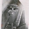 Mrs. A. Murray in the common area of her residence, with an umbrella under a leaking stairwell, at 61 East 117th Street, Harlem, New York, 1951