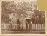 Poe Cottage on original site, man wearing boater hat at gate