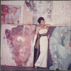 Studio portrait of Nanette Rohan Bearden modeling an evening gown with a group of paintings