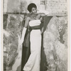 Enlargement of studio portrait of Nanette Rohan Bearden modeling an evening gown with a group of paintings, circa 1950s
