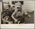 Westmoreland homesteader playing a mouth organ and a guitar, Pennsylvania