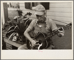 Westmoreland homesteader playing a mouth organ and a guitar, Pennsylvania