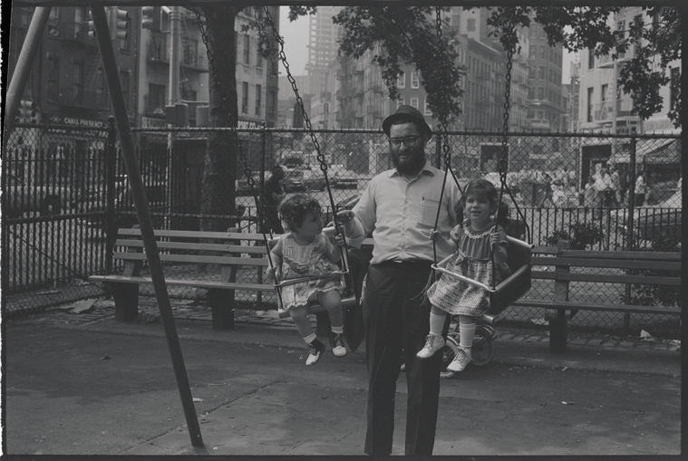 father with two toddler girls in swings