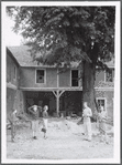 Group (5, with local boy standing on left) outside dilapidated house during performance of The Gift