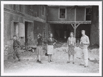 Group (5, with local boy walking on left) outside dilapidated house during performance of The Gift