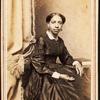 Portrait of woman seated next to tasselled curtain