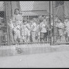 Children behind playground fence with teacher