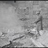 Man warming himself by a fire in a derelict lot