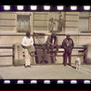 Three men and a dog on the street in front of apartment building