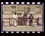 Three men and a dog on the street in front of apartment building