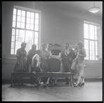Jean Rosenthal [?], Leonard Bernstein, Jerome Robbins [sitting], Arthur Laurents, Stephen Sondheim, Irene Sharaff, Hal Prince, Robert E. Griffith, and Sylvia Drulie in rehearsal for the stage production West Side Story