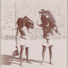 Two men carrying heavy loads on their shoulders