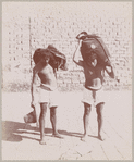 Two men carrying heavy loads on their shoulders