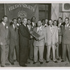 Presentation of plaque from the Vulcan Society honoring Battalion Chief Wesley Williams, presented to Williams (center) from Charles Buchanan (fourth from left), manager of the Savoy Ballroom, at the Savoy Ballroom, Harlem. Among others depicted are Dudley Glasse and Robert Lowery