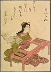 Lady seated at table with books and brushes, book in hand