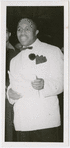 View of comedian Eddie Green, in a white jacket, speaking at an unidentified event