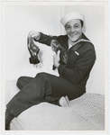 Gene Kelly in a sailor suit holding his well-worn pair of dancing shoes
