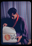 Hugh Laing in Japanese costume with chrysanthemum book