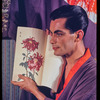 Hugh Laing in Japanese costume with chrysanthemum book