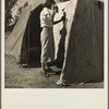 Woman in a California pea pickers' camp, mending the tent