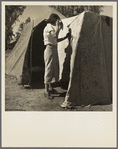 Woman in a California pea pickers' camp, mending the tent