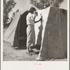Woman in a California pea pickers' camp, mending the tent
