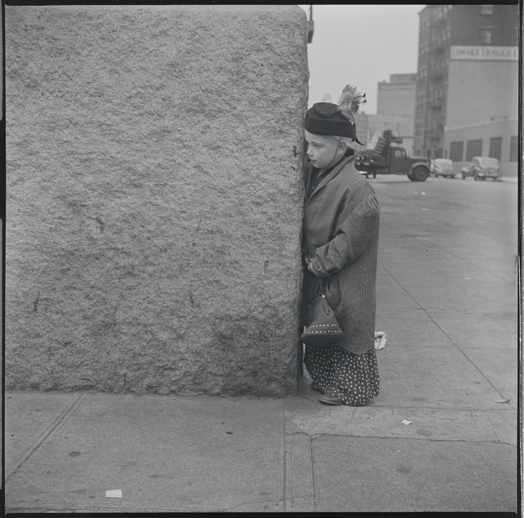 Child in costume hiding behind a corner. New York, NY