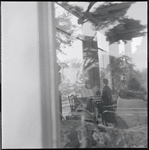 Woman playing the piano, seen through a glass window