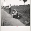A hitchhiking family waiting along the highway in Macon, Georgia. The father repairs sewing machines, lawn mowers, etc. He is leaving Macon, where a license is required for such work (twenty-five dollars) and heading back for Alabama