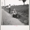 A hitchhiking family waiting along the highway in Macon, Georgia. The father repairs sewing machines, lawn mowers, etc. He is leaving Macon, where a license is required for such work (twenty-five dollars) and heading back for Alabama