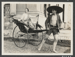 Ruth St. Denis sitting in rickshaw being pulled by Ted Shawn in Singapore