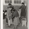 Camper receives help in fitting a coat from Works Progress Administration (WPA) sewing instructor. Shafter camp for migratory agricultural workers (Farm Security Administration-FSA), California