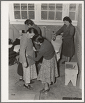 Camper receives help in fitting a coat from Works Progress Administration (WPA) sewing instructor. Shafter camp for migratory agricultural workers (Farm Security Administration-FSA), California
