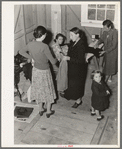 Camper receives help in fitting a coat from Works Progress Administration (WPA) sewing instructor. Shafter camp for migratory agricultural workers (Farm Security Administration-FSA), California