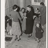 Camper receives help in fitting a coat from Works Progress Administration (WPA) sewing instructor. Shafter camp for migratory agricultural workers (Farm Security Administration-FSA), California