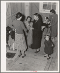 Camper receives help in fitting a coat from Works Progress Administration (WPA) sewing instructor. Shafter camp for migratory agricultural workers (Farm Security Administration-FSA), California