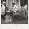 Near Douglas, Georgia. Sharecroppers grade the cured leaves on the porches and sort them to go to the tobacco auction