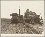 Loading bins of potato planter with fertilizer and seed from trailer at edge of field. Kern County, California
