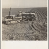 Kern County, California. Large-scale mechanized farming. The potato planter, operated by a crew of three men, makes the rows, fertilizes and plants potatoes in one operation