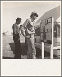 Farm Security Administration (FSA) migratory labor camp (emergency). Migratory workers, in camp for the pea harvest, scan the bulletin board at entrance