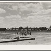 Tulare County, California. Farm Security Administration (FSA) camp for migrant agricultural workers. Nursery school children. Row of prefabricated steel shelters in which their families live shown in background