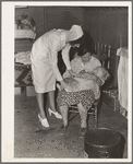 Tulare County, California. Farm Security Administration (FSA) camp for migratory agricultural workers at Farmersville. Nurse of Agricultural Workers' Health and Medical Association (FSA) is assigned to camp. Photo shows her attending sick baby