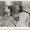 Tulare County, California. Farm Security Administration (FSA) camp for migratory agricultural workers at Farmersville. Nurse of Agricultural Workers' Health and Medical Association attends sick migrant woman while awaiting doctor