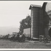 Yard of one of the eight cooperating farmers whose corn is being stored on this day. Note the newly built silo and the ensilage cutter in use. Near West Carlton, Yamhill Country, Oregon. General caption number 58