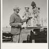 Franklin Schroeder and his older boys in the yard. He is giving them the "last of the watermelon of the season." Dead Ox Flat, Malheur County, Oregon. General caption number 67-111