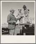 Franklin Schroeder and his older boys in the yard. He is giving them the "last of the watermelon of the season." Dead Ox Flat, Malheur County, Oregon. General caption number 67-111