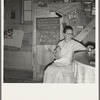 Mrs. Hull in one-room dugout basement home (note blackboard.) "I wanted a blackboard for a long time for my Bible verses, to keep them in our mind. Got it last year." Dead Ox Flat, Malheur County, Oregon. General caption number 67-111